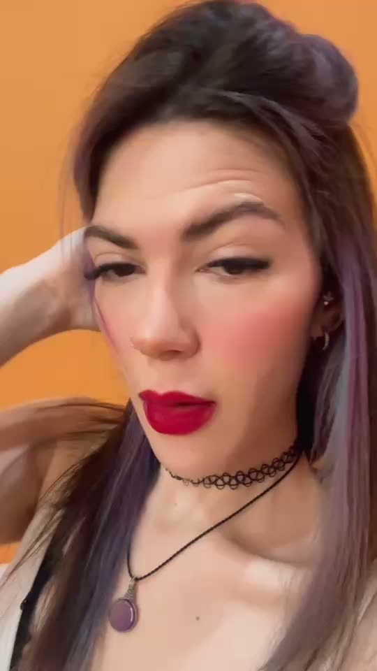 Woman with violet-streaked hair and red lipstick on camera