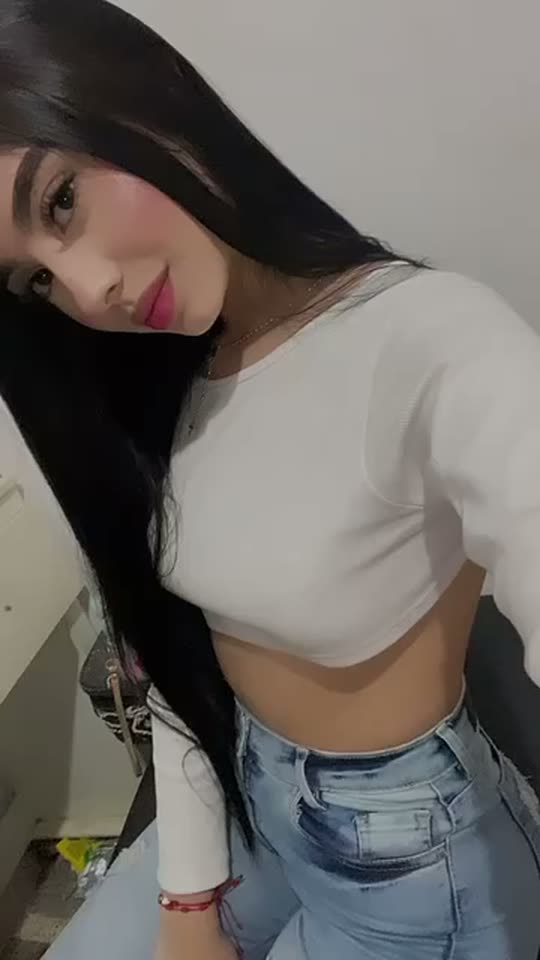 Woman with long black hair in a white top filming a short video
